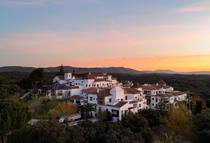road between green grass field near mountains under blue and brown sky at golden hour