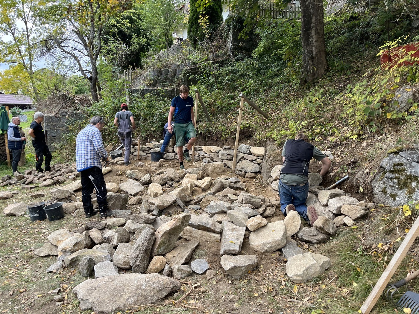 Teilnehmer setzen Bau von Stützmauer fort (1/3)