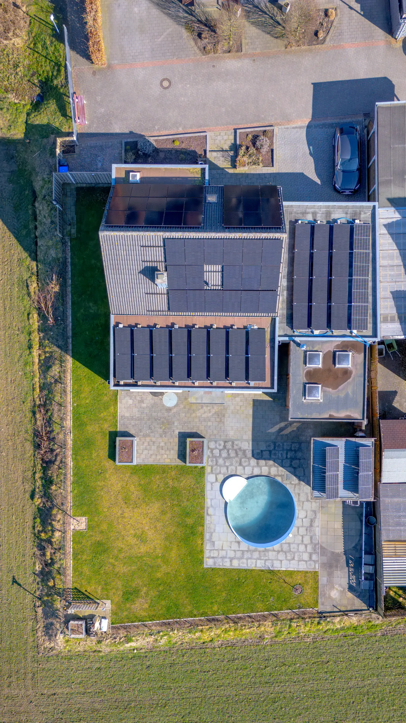 Senkrechte Drohnenaufnahme des Einfamilienhauses in Ochtrup aus der Vogelperspektive mit Blick auf Rundbecken-Pool, Garten, Terrasse und großflächige Solaranlage auf allen Dachflächen