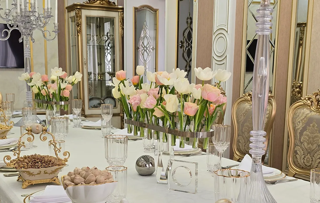 Luxurious dining table set with tulip arrangements, ornate glassware, and elegant decor in a richly decorated room.