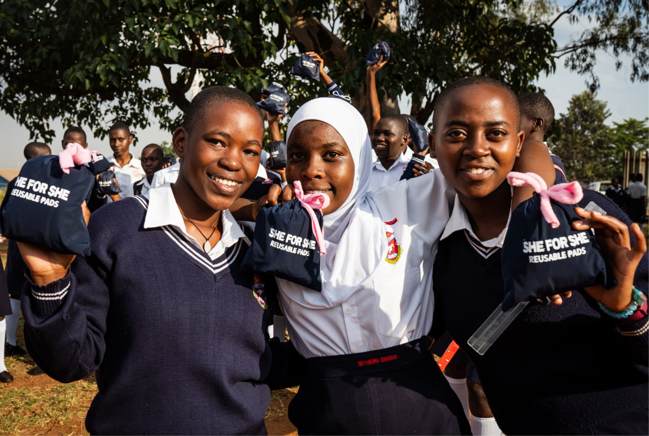 Belinda and two other girls holding SHE FOR SHE menstrual pads. 