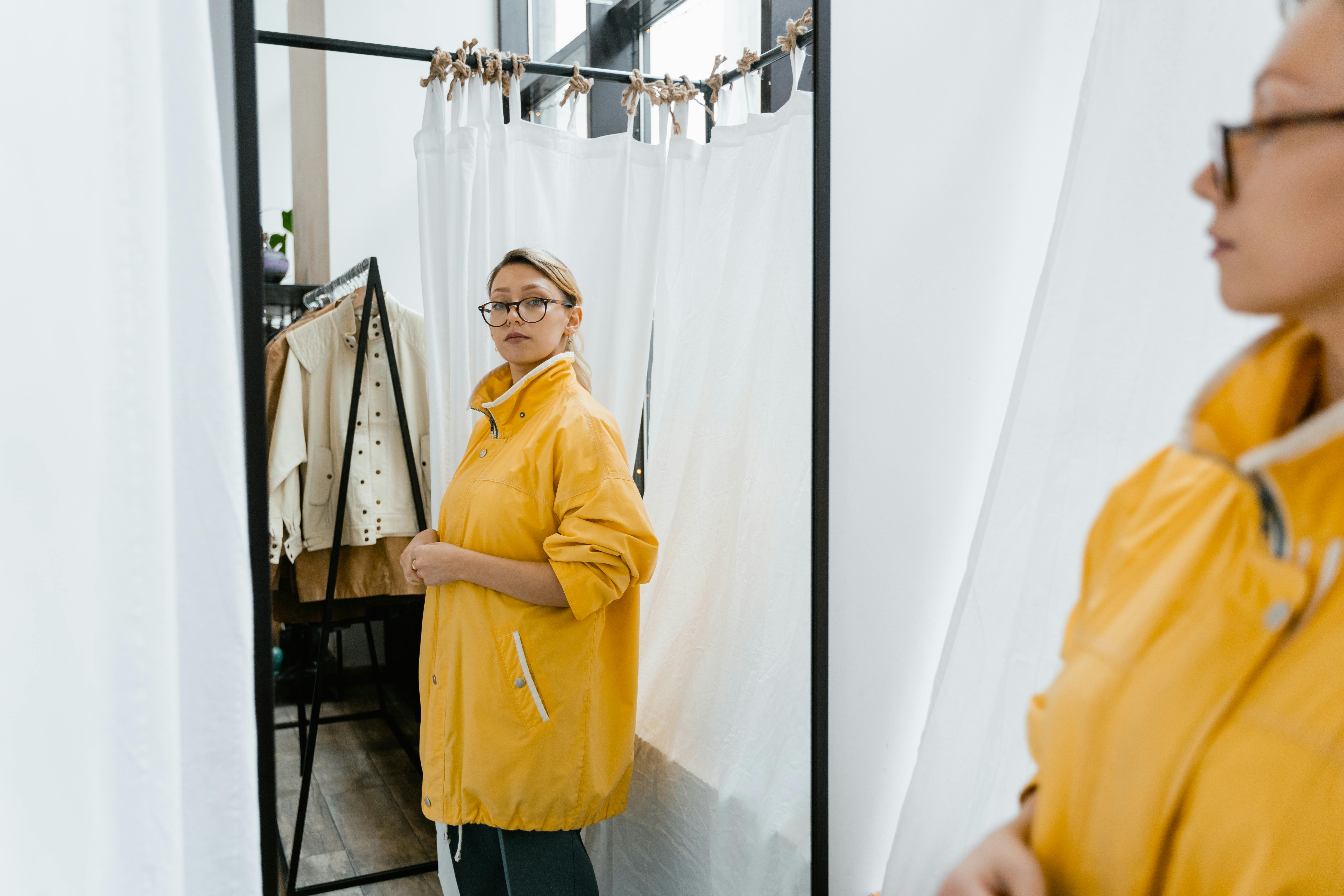 Photo by MART  PRODUCTION: woman in yellow jacket standing in front of a mirror