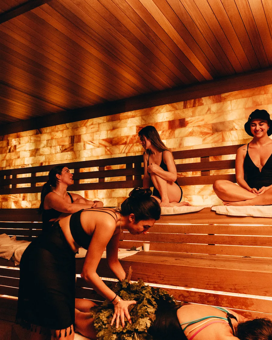 Group seated in a sauna wearing swimwear, demonstrating appropriate attire for those wondering what to wear in a sauna setting.