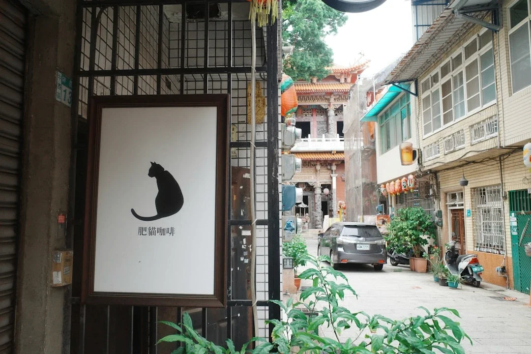 A sign with a black cat silhouette on a street.