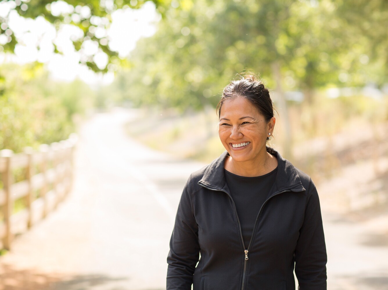 woman smiling as she hits her walking weight loss goals on an outside path