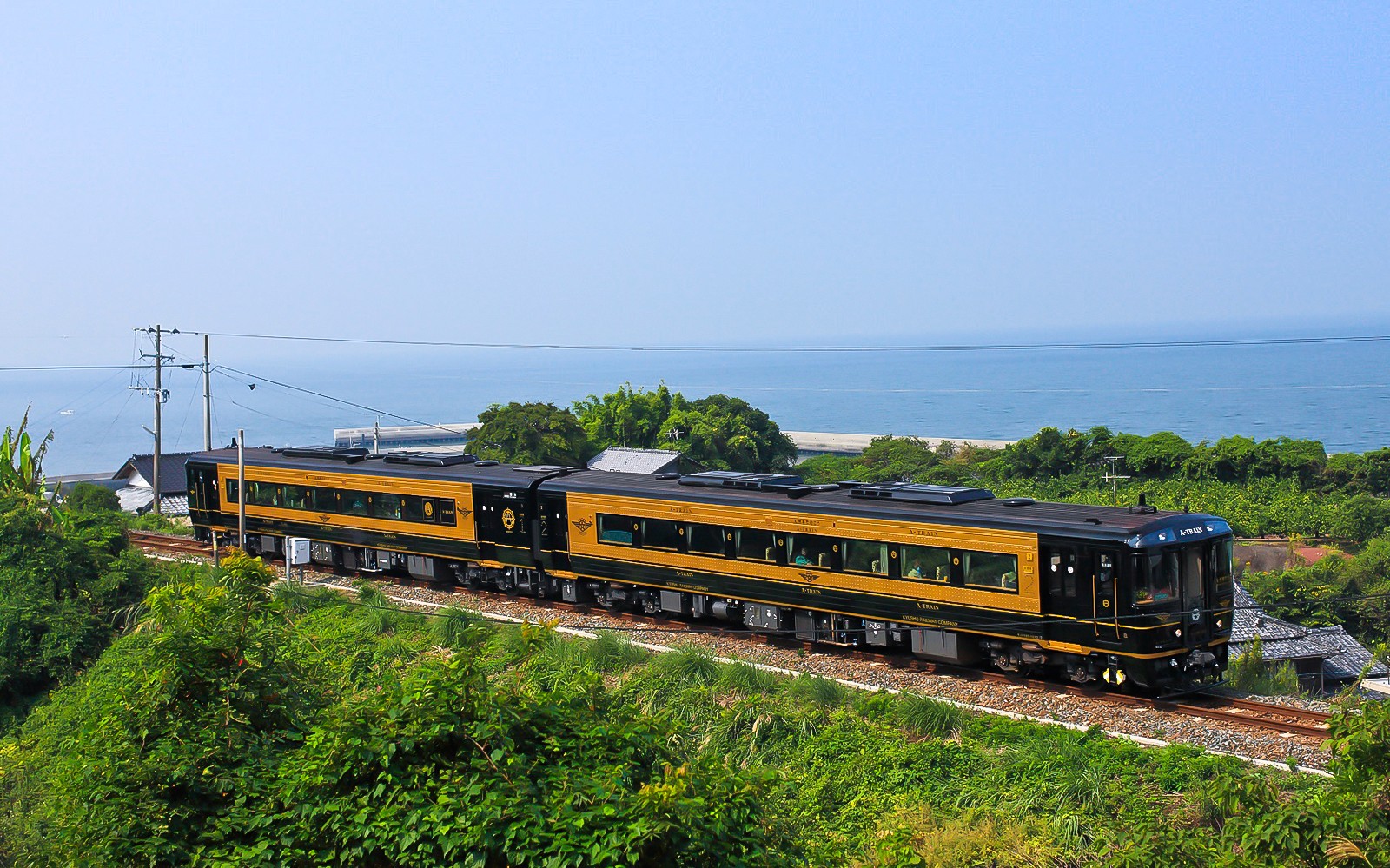 Train traveling along Kyushu coast with ocean view, JR North Kyushu Rail Pass.