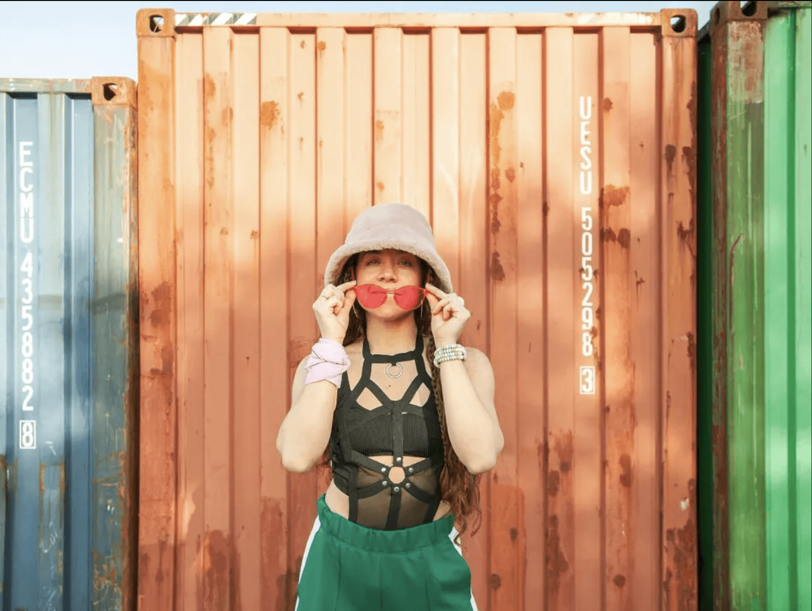 Woman with heart sunglasses against shipping containers.