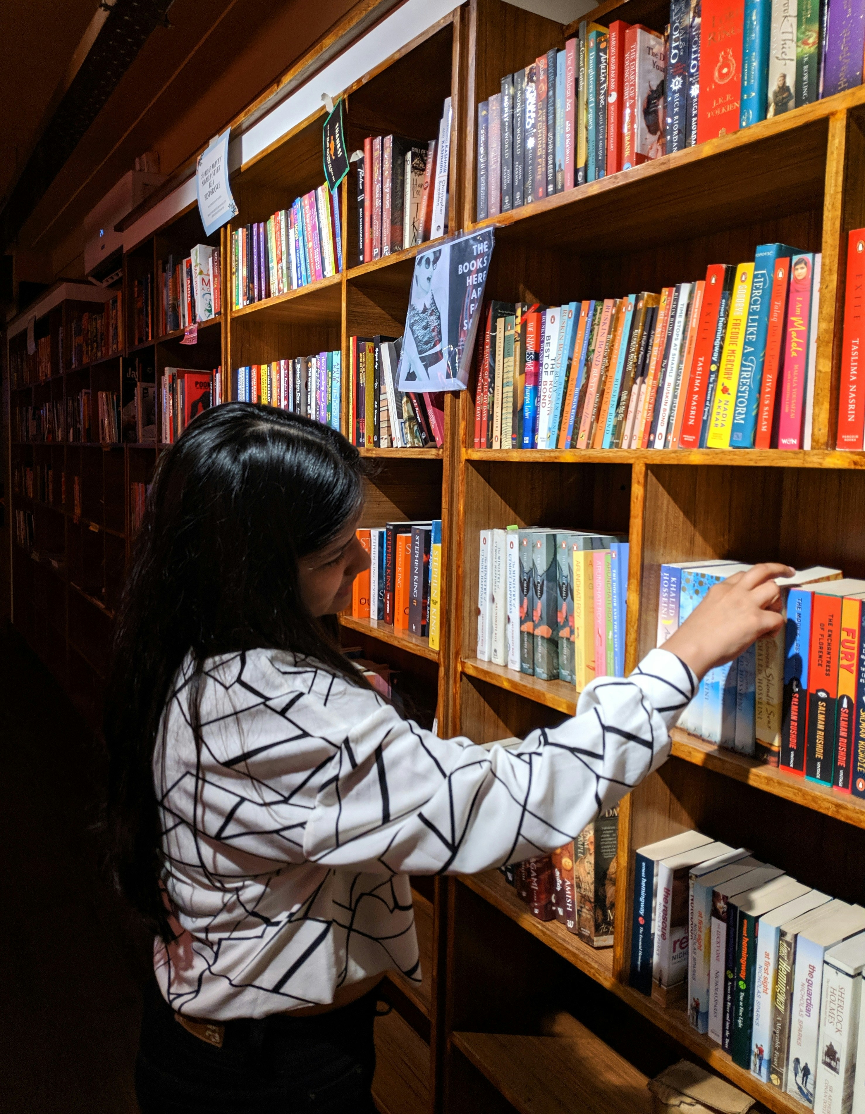 A woman looking at books on a book shelf