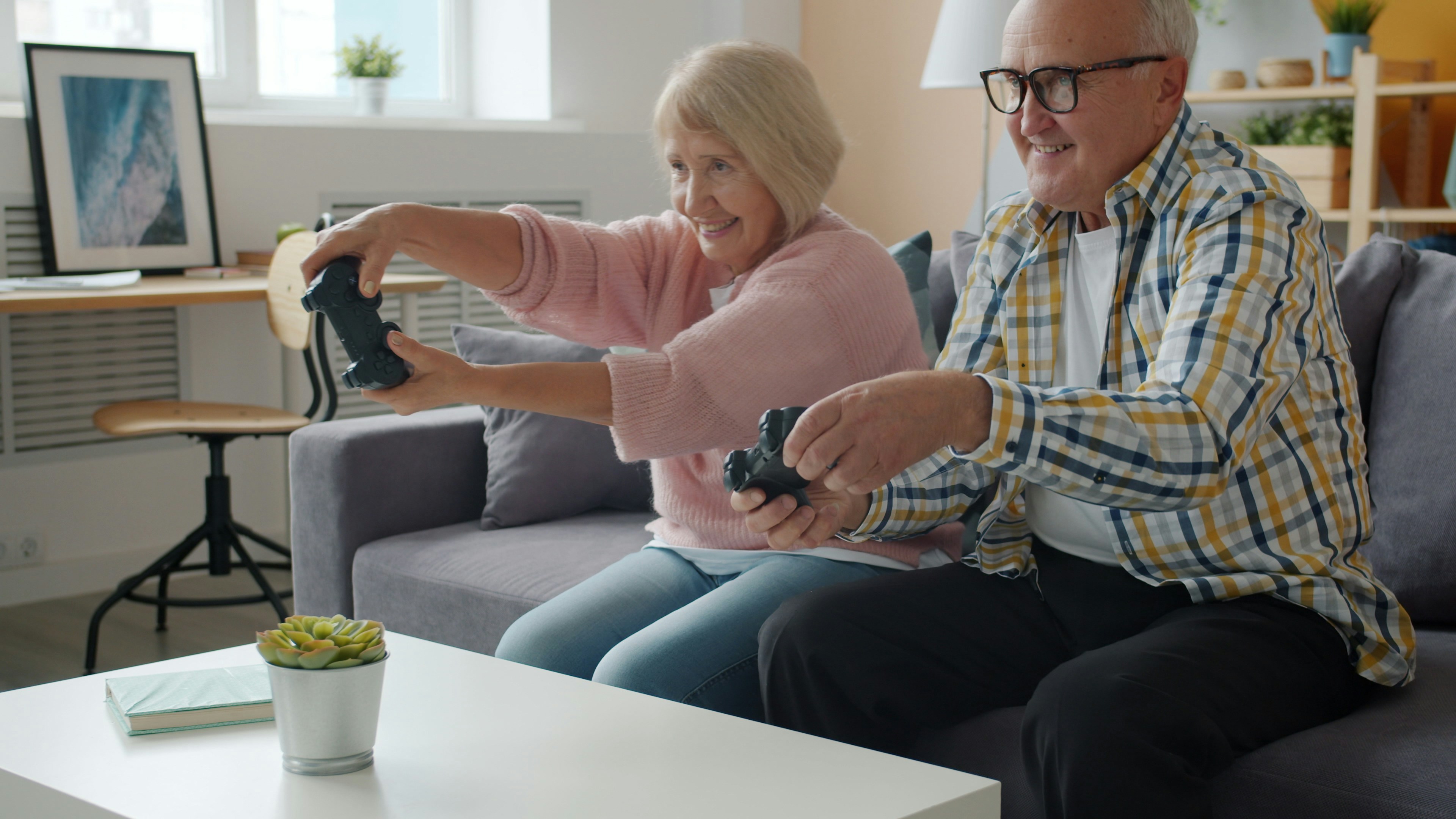 Elderly couple playing video games on the couch.