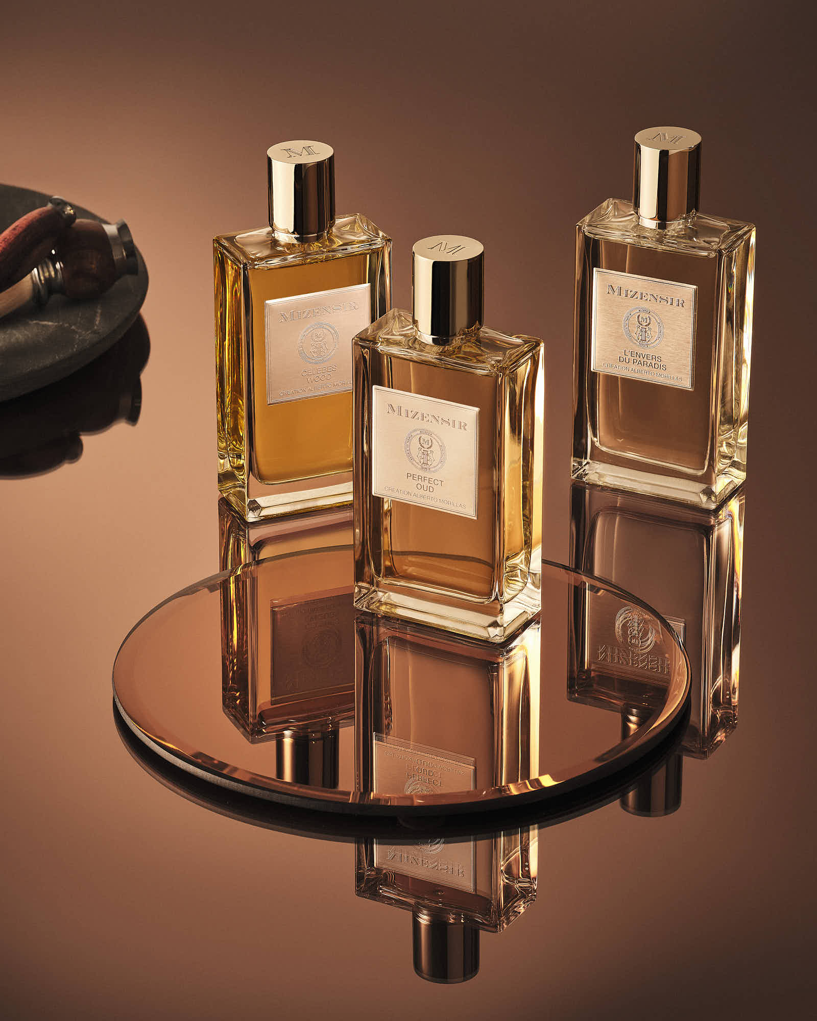 Three elegant perfume bottles are arranged on a reflective surface, set against a warm, muted background.