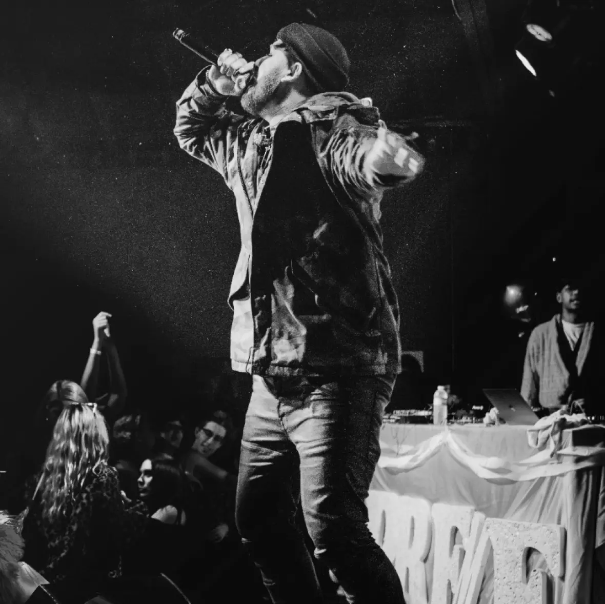 A rap artist is captivating the audience with a powerful performance, microphone in hand, at a rap concert.