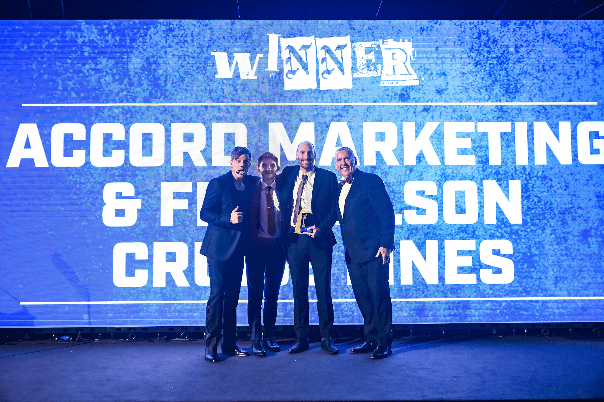 People seated at a table with laptops and water bottles, engaged in discussion in a bright meeting room.