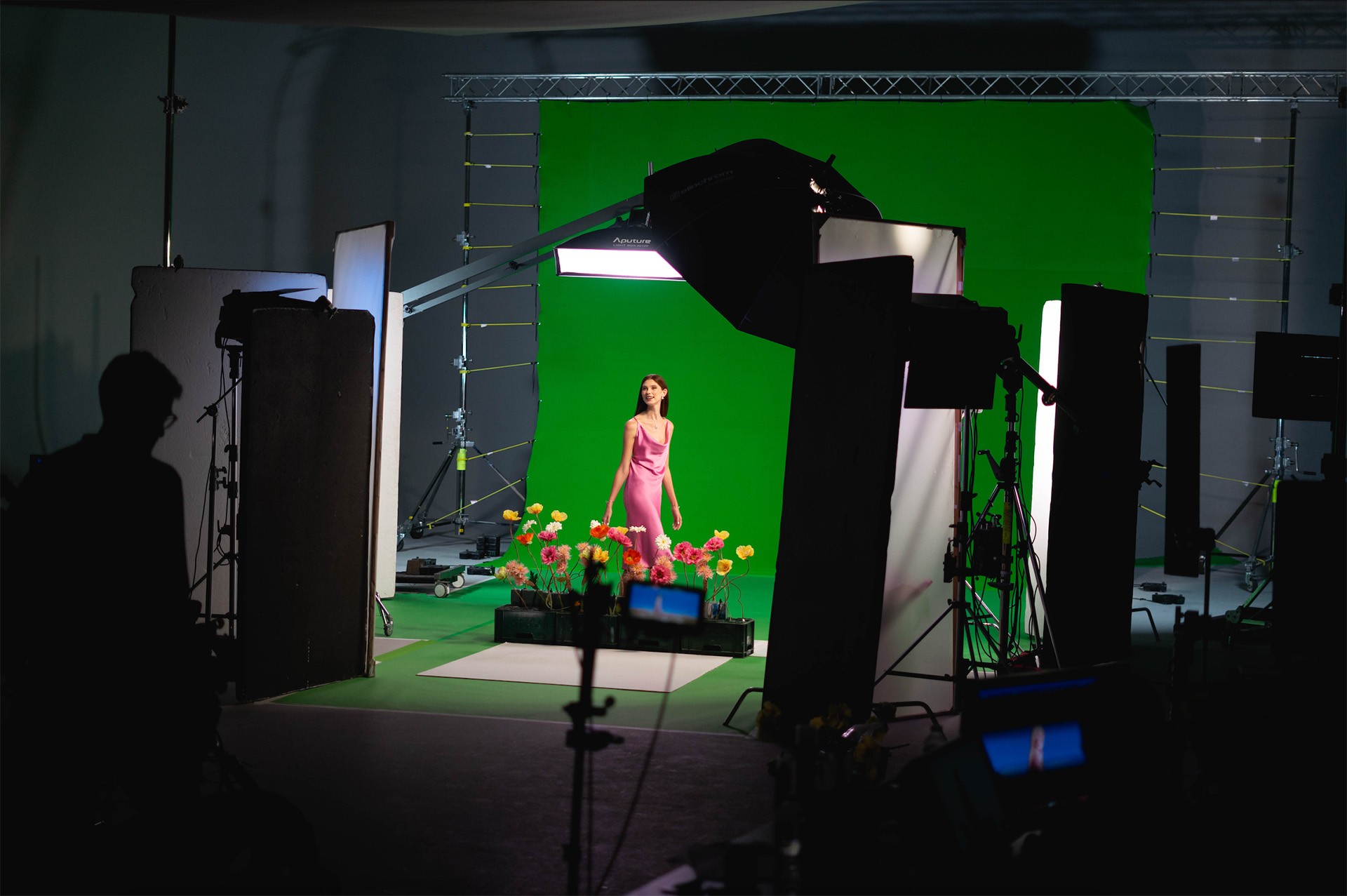 Behind the scenes image of a photographic studio with a model stood infront of a green screen