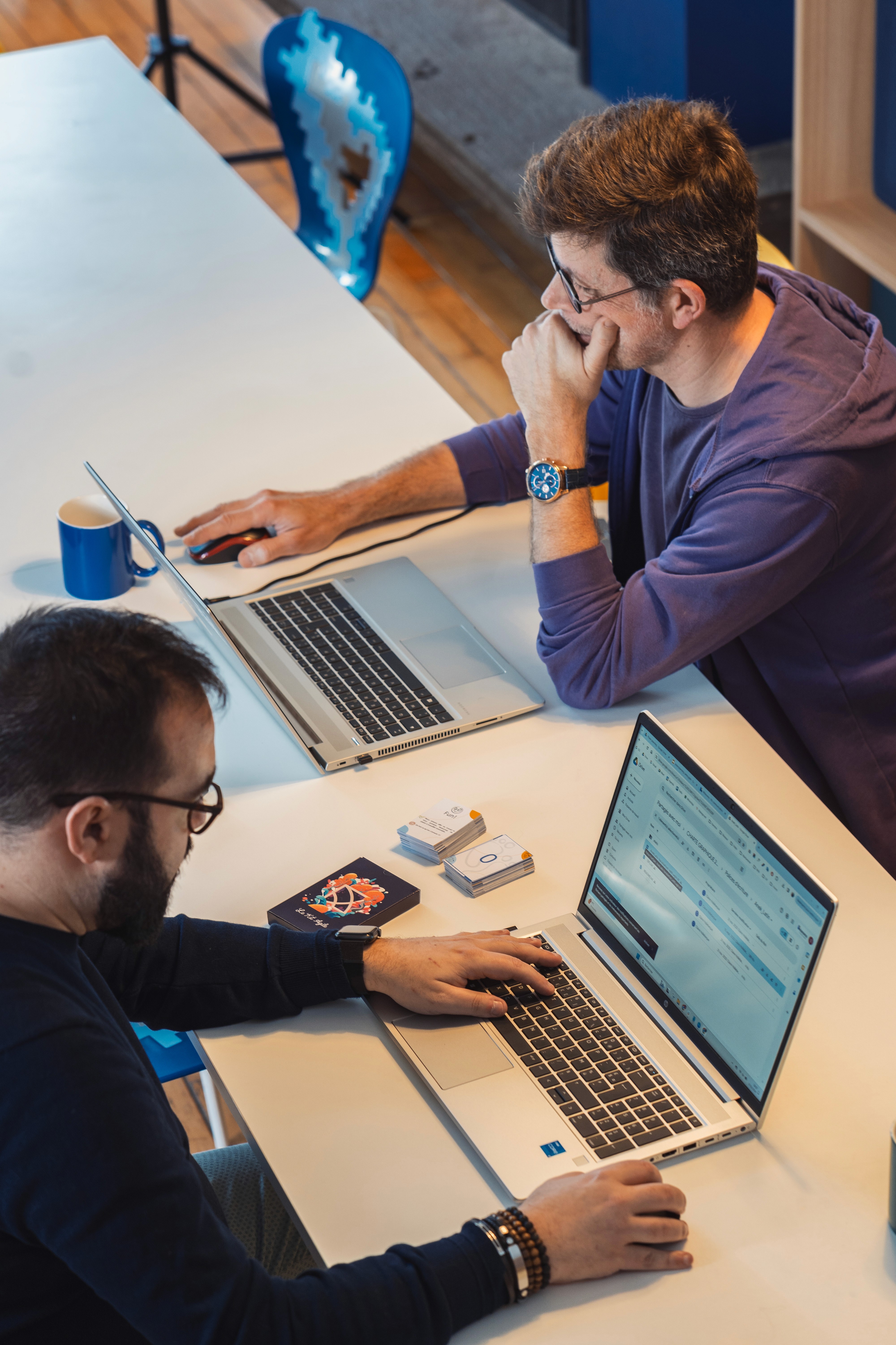 deux personnes face à face qui travaillent sur un ordinateur