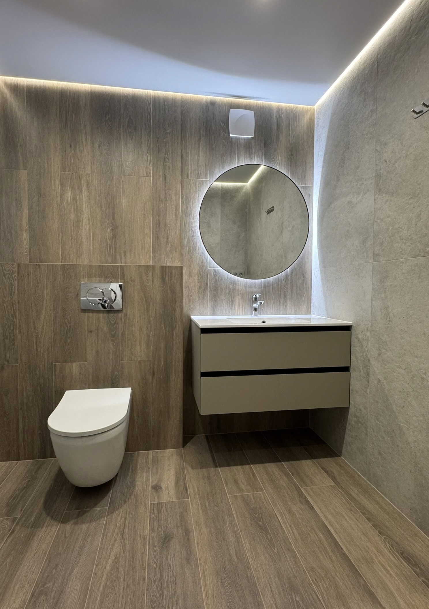 Санвузол з круглим дзеркалом, підвісною тумбою і дерев’яною плиткою