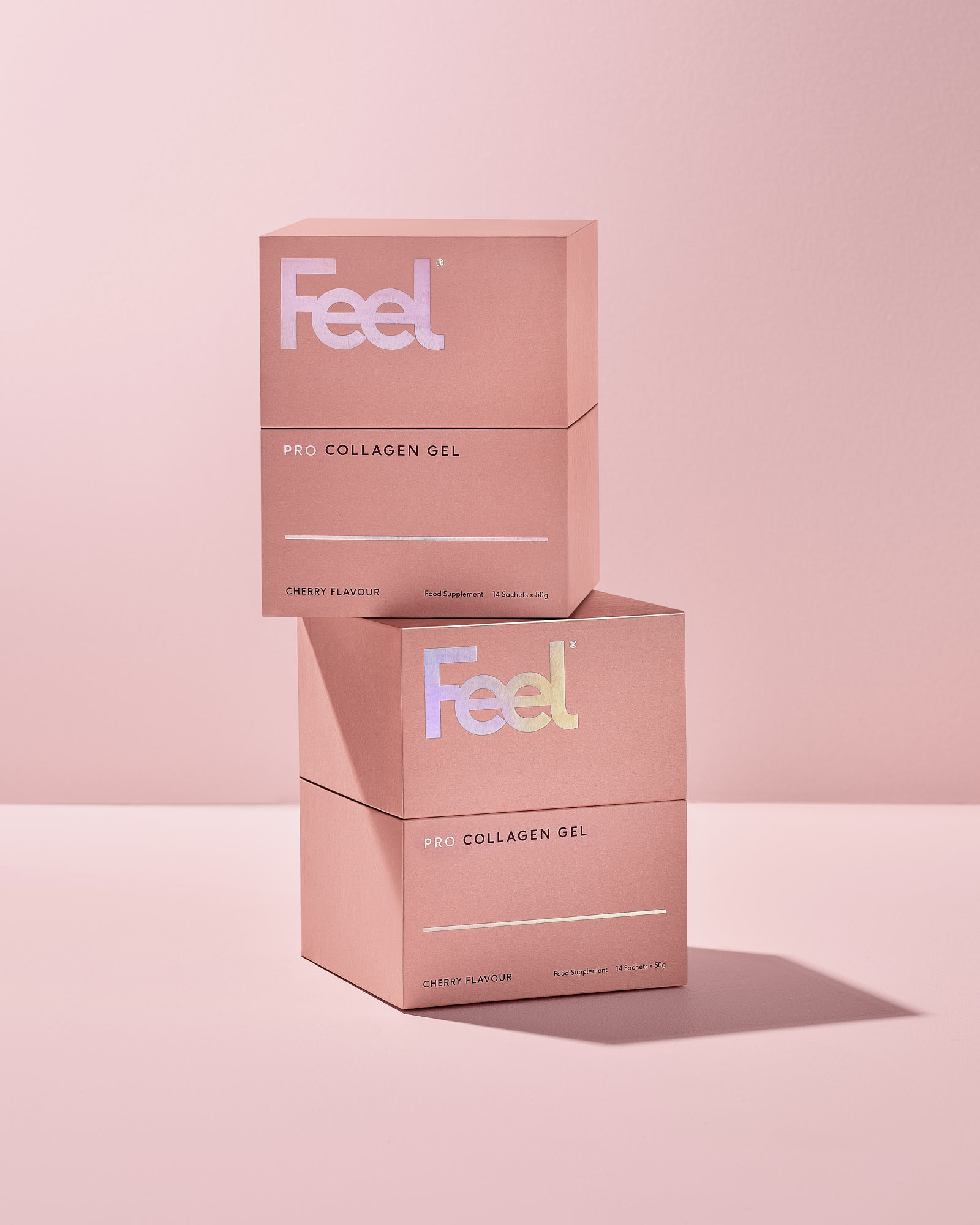 Two stacked pink boxes on a soft pink background, featuring minimalistic branding in white text.