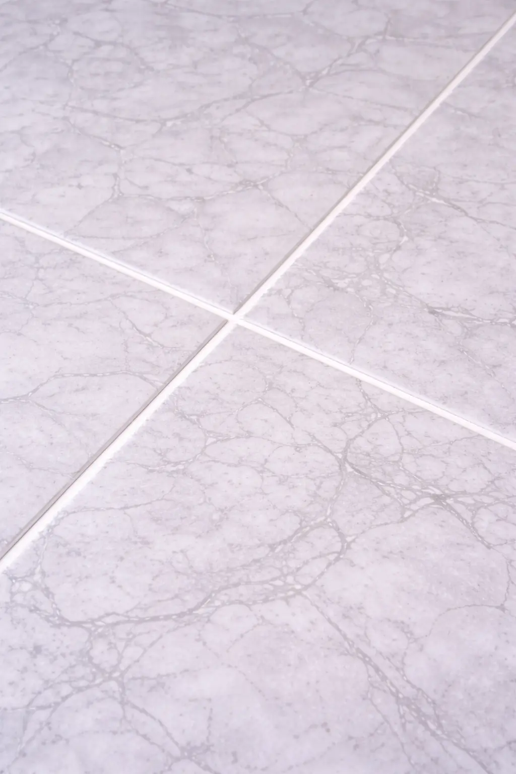 Deeply cleaned marble-patterned floor tiles with bright white, dust-free grout lines after professional post-construction floor care.