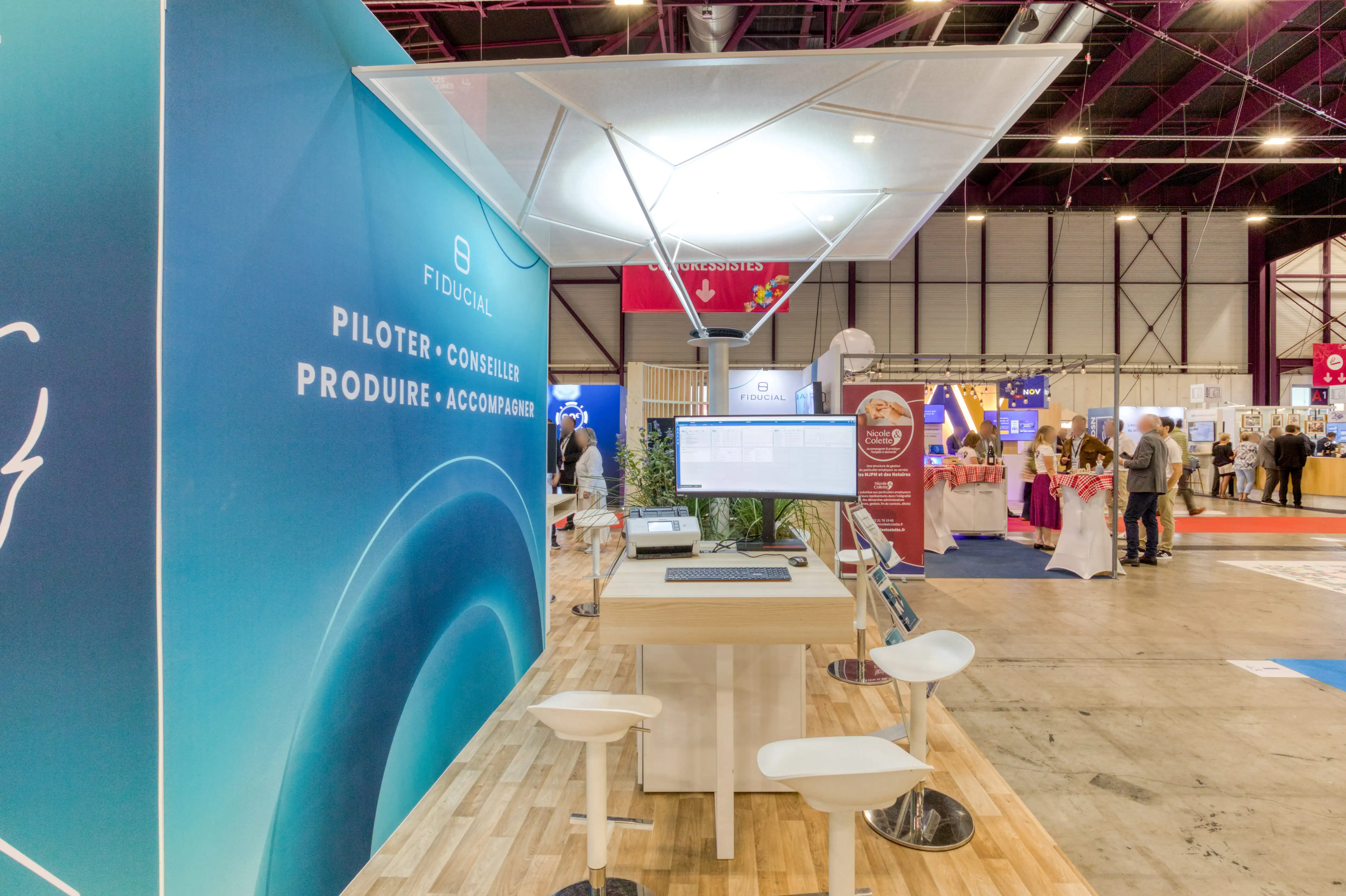 Vue latérale du stand Fiducial avec espace d’accueil, auvent blanc et zone d’échanges