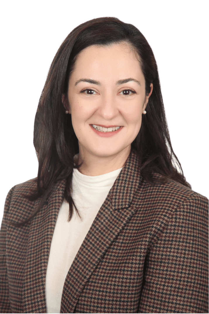 Frau mit braunem Anzug und dunklen Haaren lächelt in die Kamera und sieht vertrauenswürdig aus. 