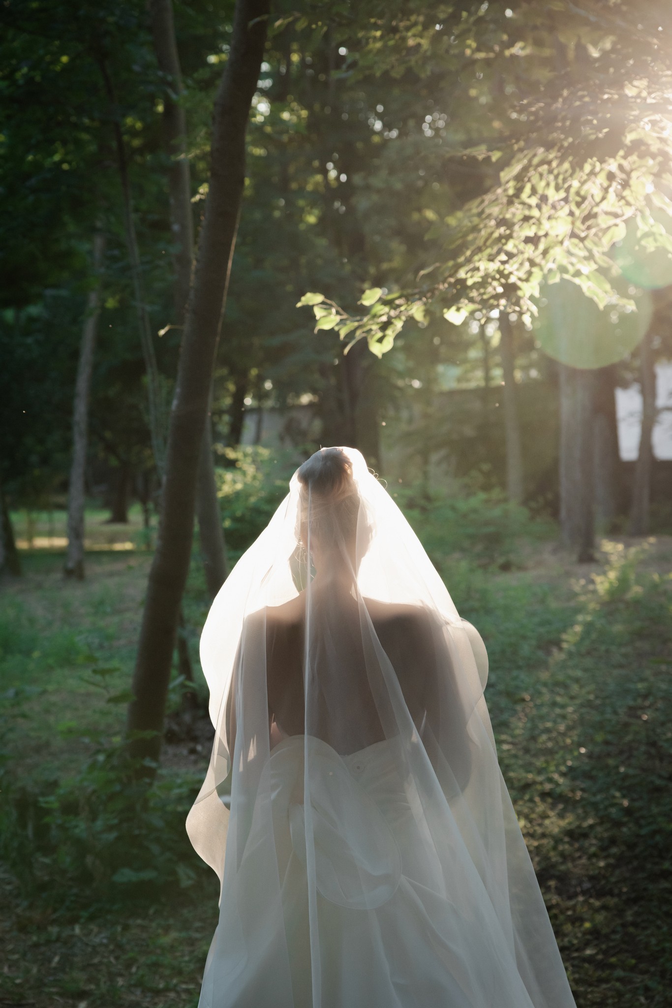 Sposa di spalle nel velo a Villa Malenchini, luce naturale tra alberi, reportage Fotolize di matrimonio in Toscana