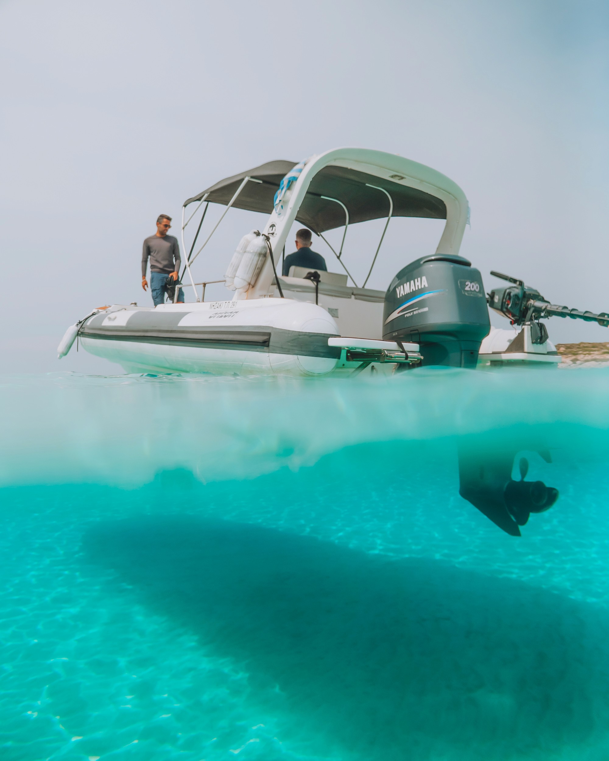 White Orizon 24 motor boat with Yamaha outboard engine floating in crystal-clear turquoise waters with passengers aboard.
