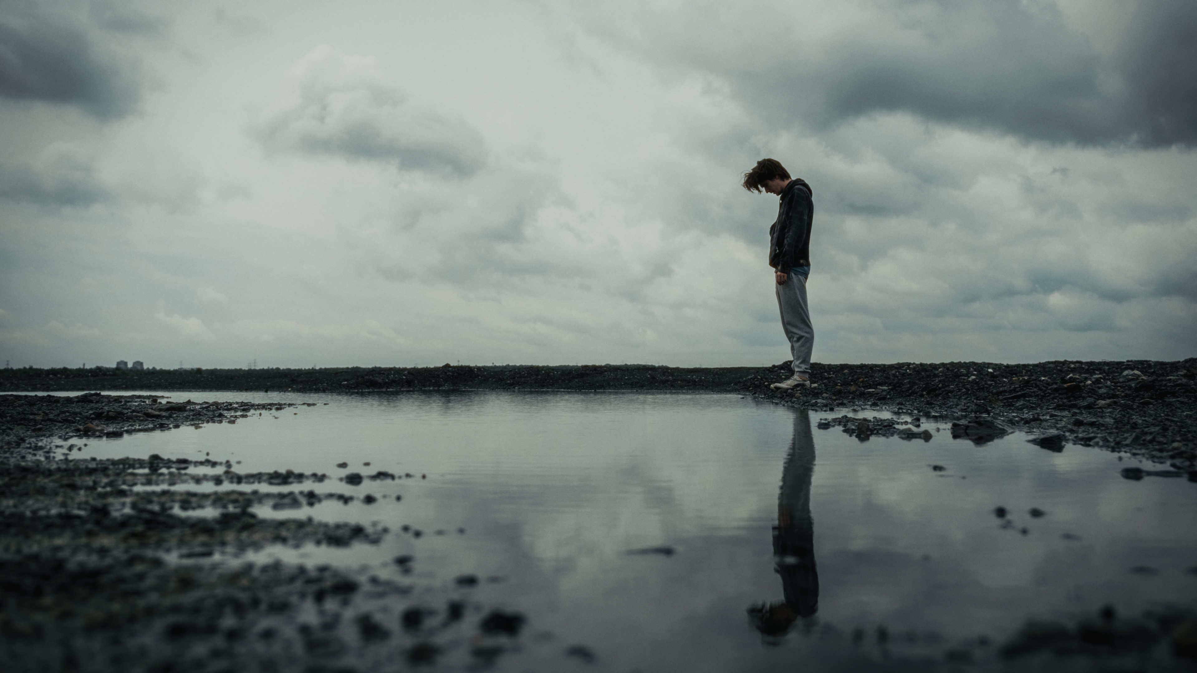 Post-industrial landscape photography featuring a tiny human silhouette against a cloudy sky.