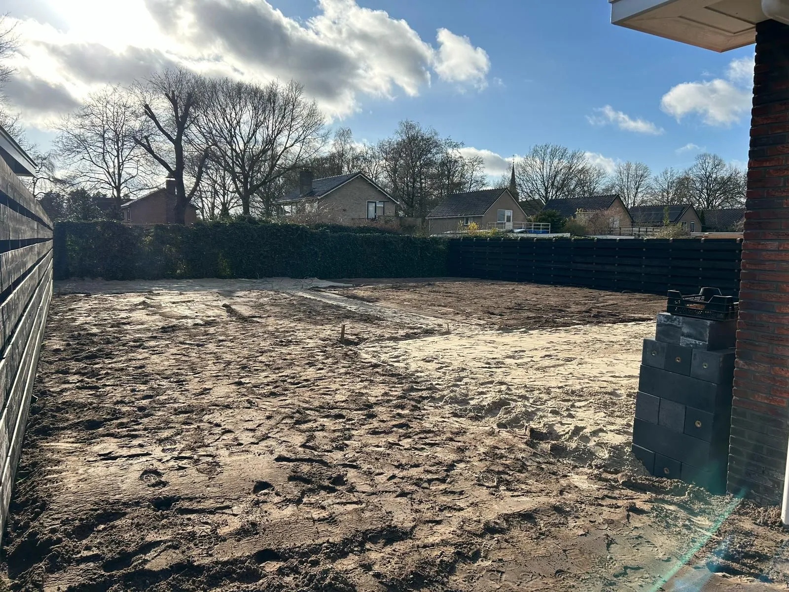 Grote kale nieuwbouwtuin met omheining en zicht op omliggende huizen, klaar voor kindvriendelijke en onderhoudsvriendelijke inrichting.