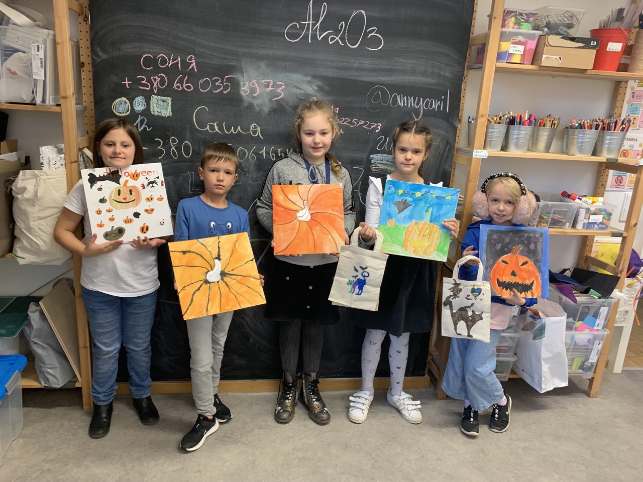 Kinder stehen zusammen und präsentieren die Bilder, die sie gemalt haben.