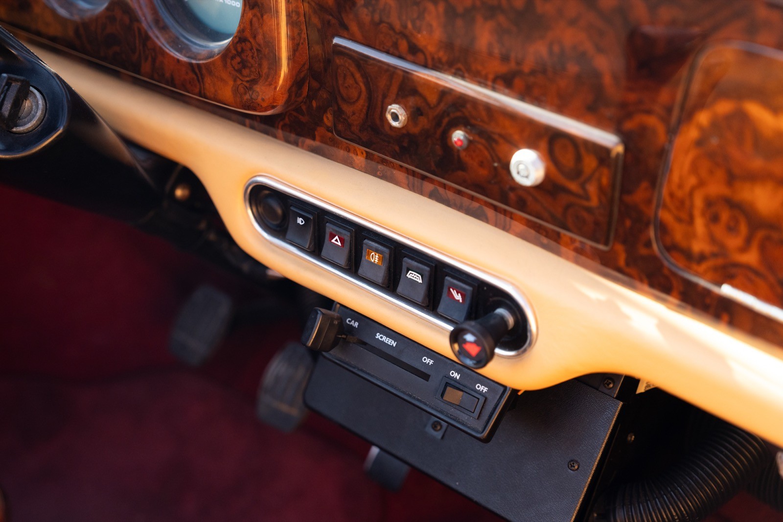 Close-up of a classic car dashboard featuring wooden trim and control buttons.