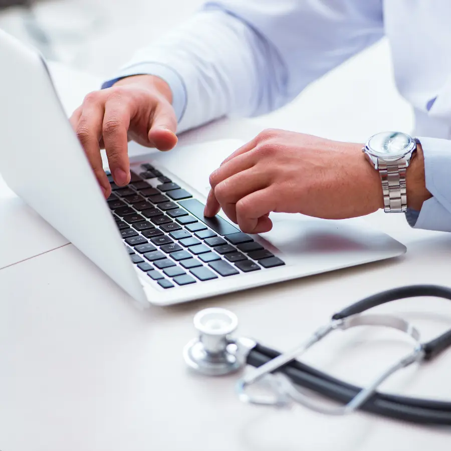 AI for doctors assisting as a physician types on a laptop with a stethoscope on the desk