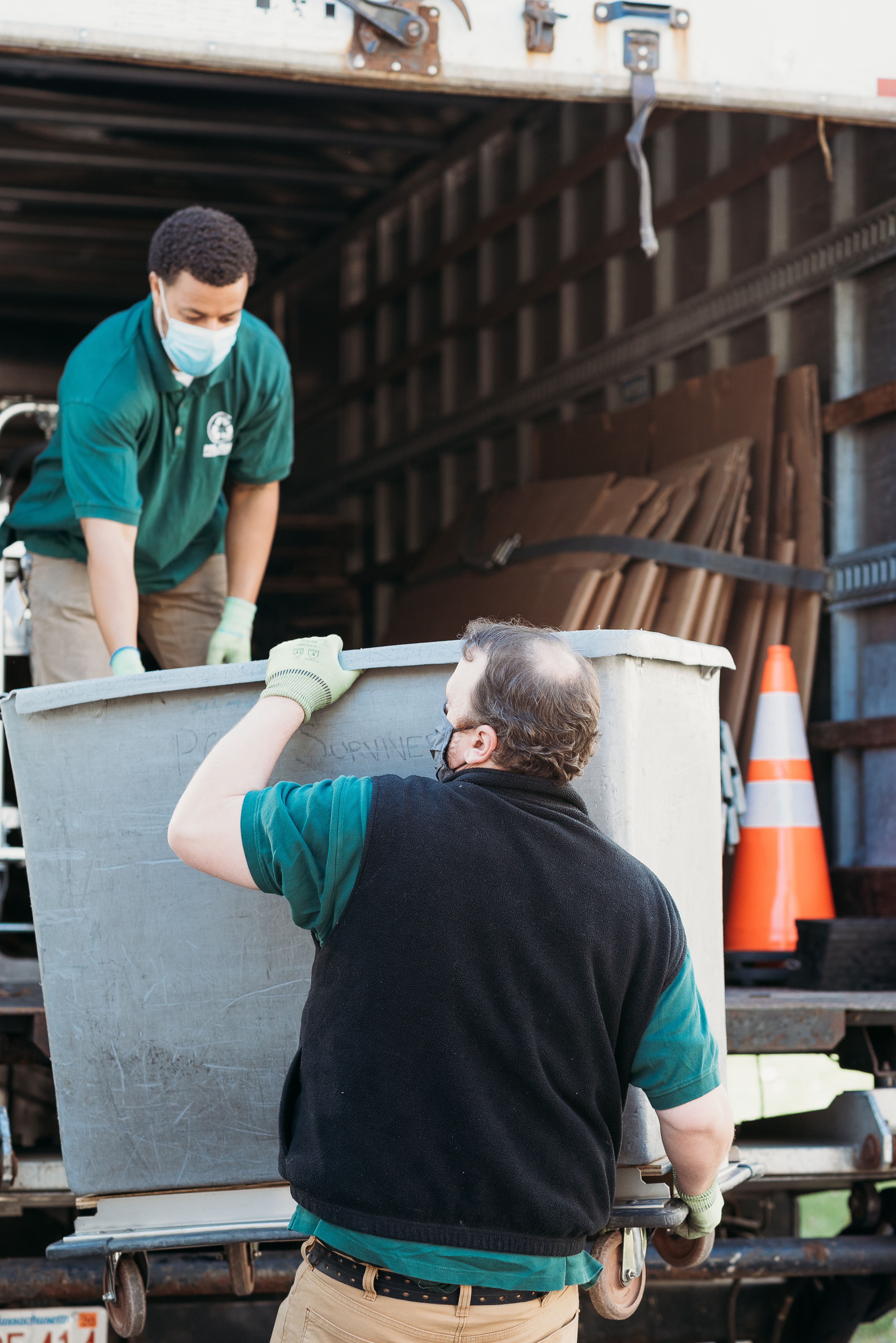 Man lifting container of recycled material into truck