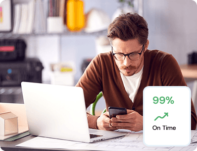 Person working on a laptop and smartphone with a dashboard showing 99% on-time performance, representing mobile facility management.
