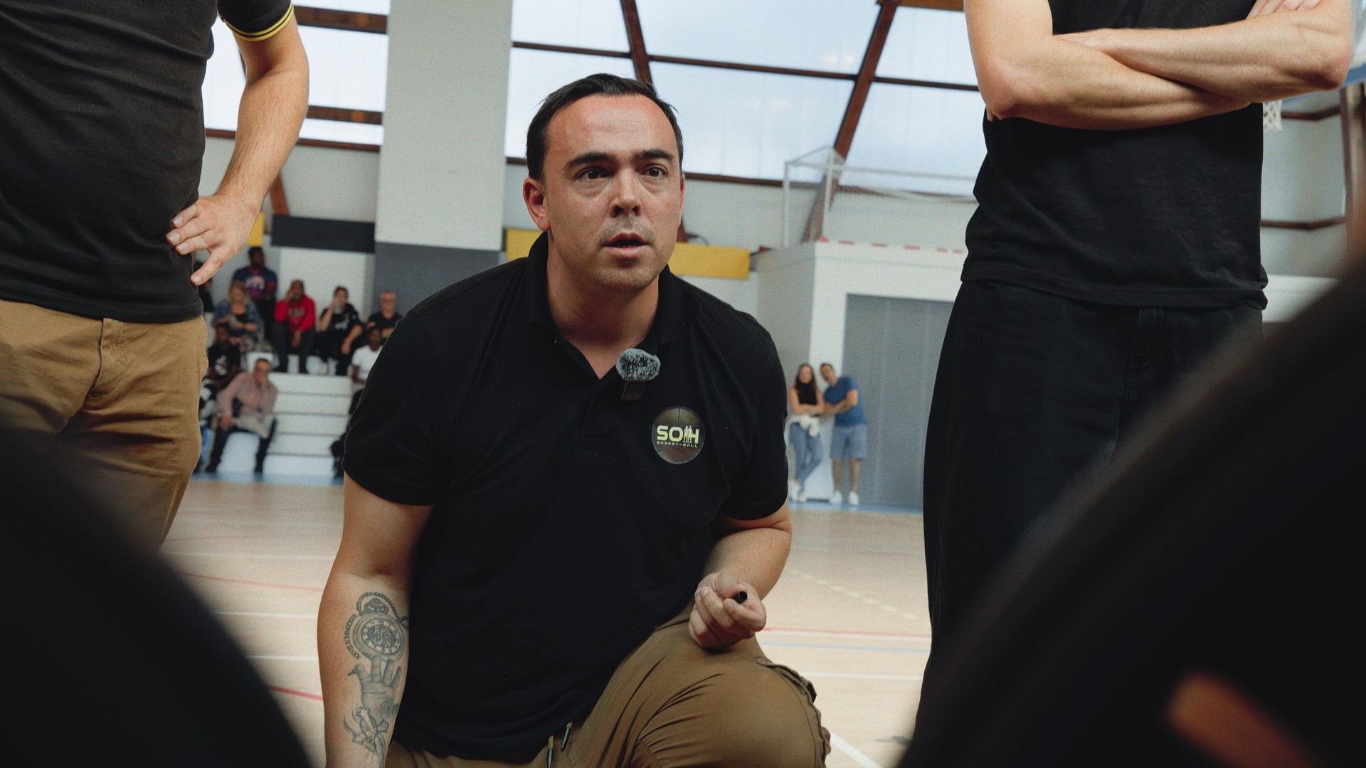Entraîneur concentré, en pleine discussion tactique avec son équipe de basketball U15F.
