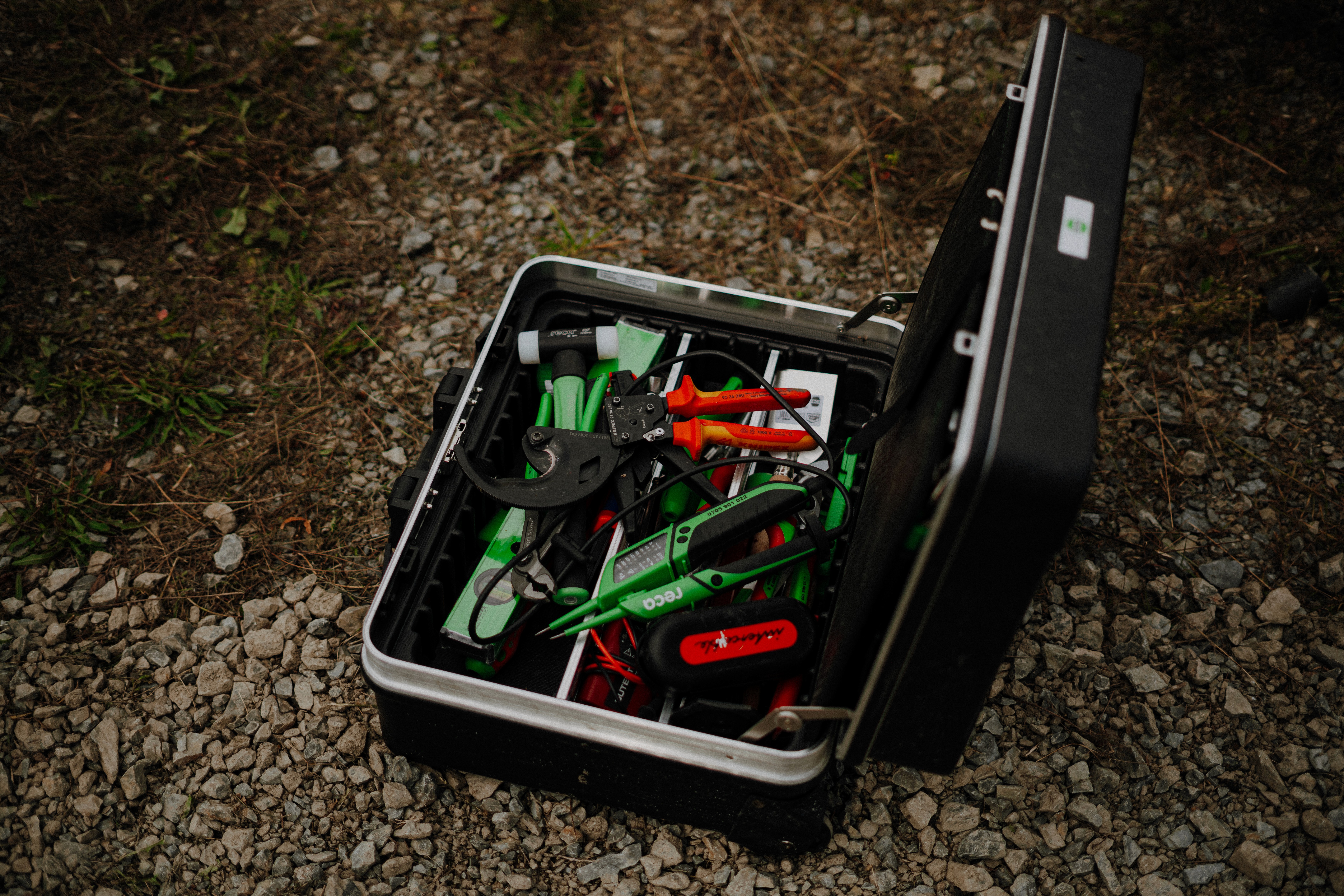 Eine schwarze Werkzeugkiste ist geöffnet und zeigt verschiedene farbenfrohe Werkzeuge sowie Gartenzubehör, die ordentlich im Inneren angeordnet sind.