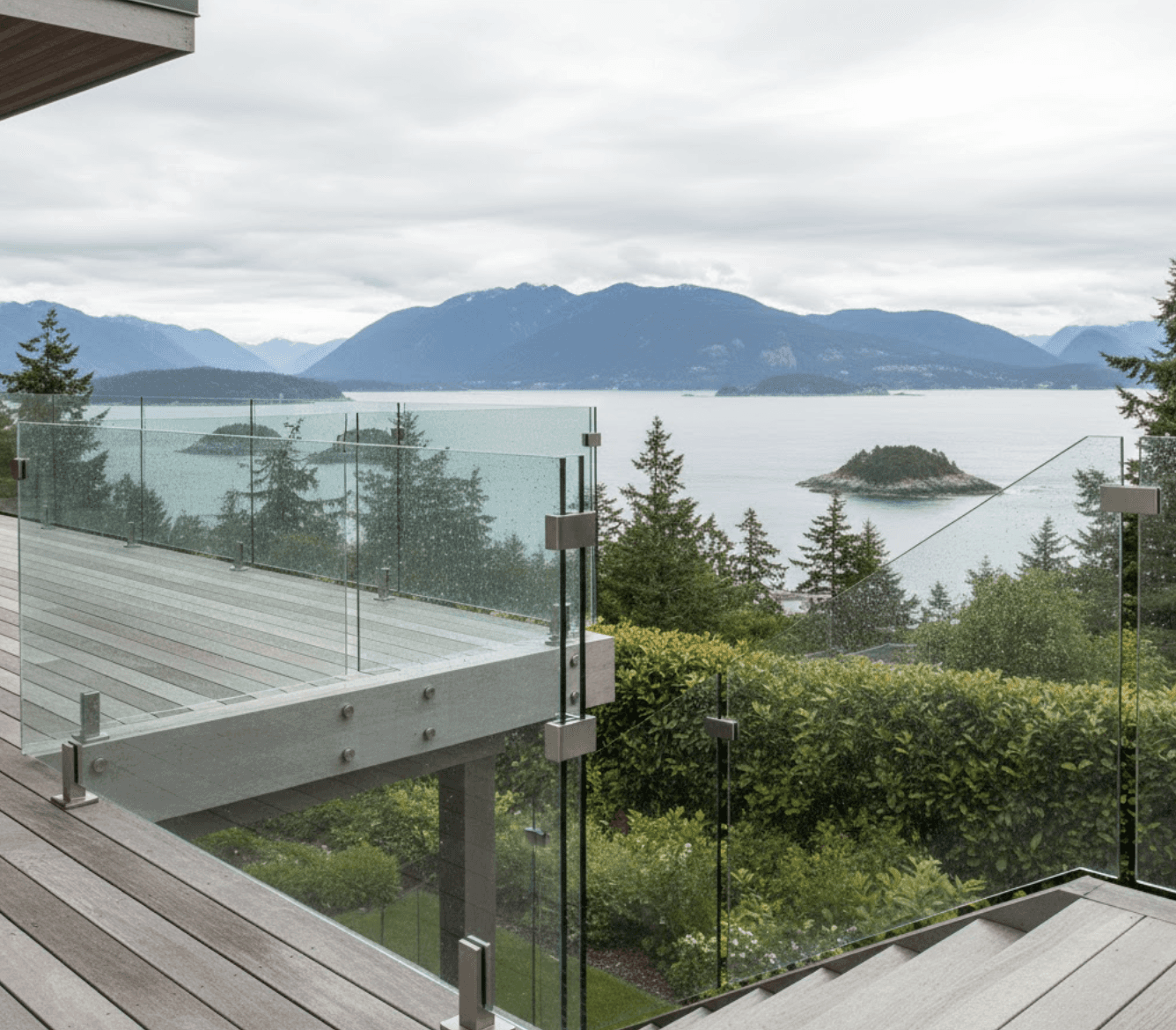 Exterior glass staircase connecting elevated wooden deck to garden level. Frameless glass panels with marine-grade stainless steel hardware.