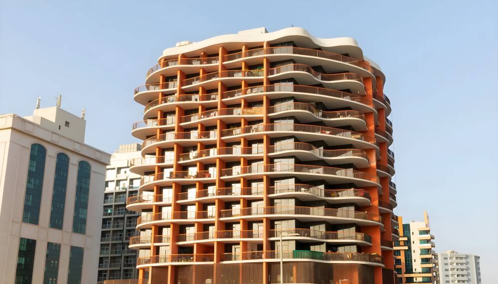 A tall building with a curved facade, known as Binghatti Horizons, stands prominently beside the road.