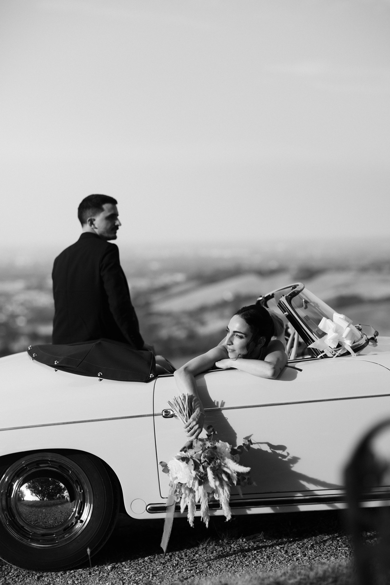 Sposi seduti su auto d'epoca al tramonto nel Parco di Montebello, reportage di matrimonio a Parma
