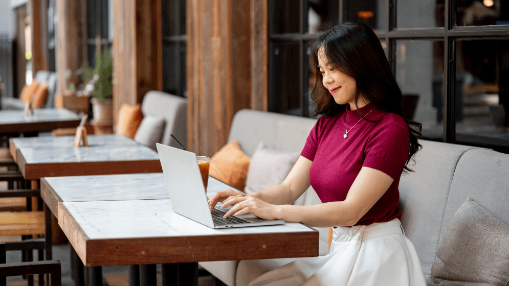 A Malaysian business owner sending an email on her laptop