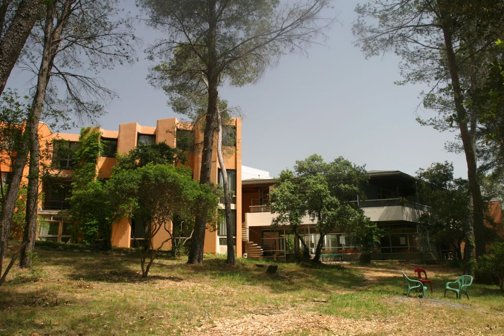 Bâtiment classique en pierre avec des caractéristiques en forme d'arc, entouré d'arbres matures et d'un paysage verdoyant