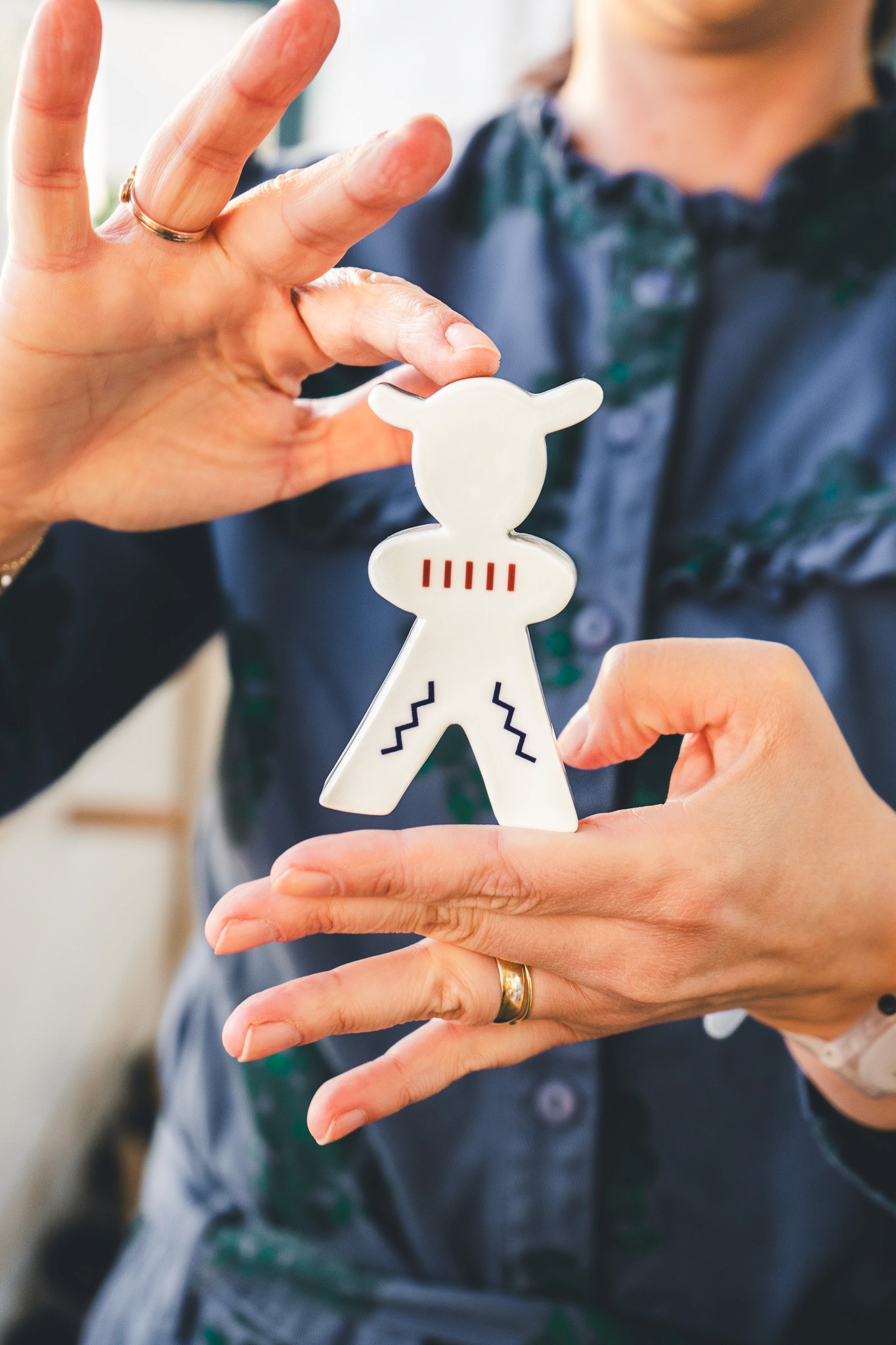 Detail keramickej hračka-sochy v tvare postavy, držanej v rukách – súčasť série inšpirovanej detstvom, folklórom a galandovským výtvarným štýlom.