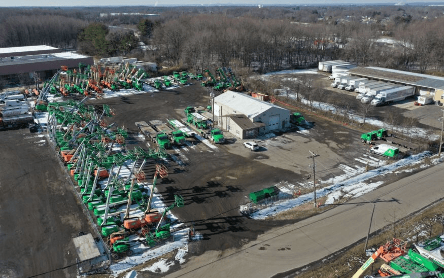 Aerial view of a storage yard holding green and orange lift equipment in winter