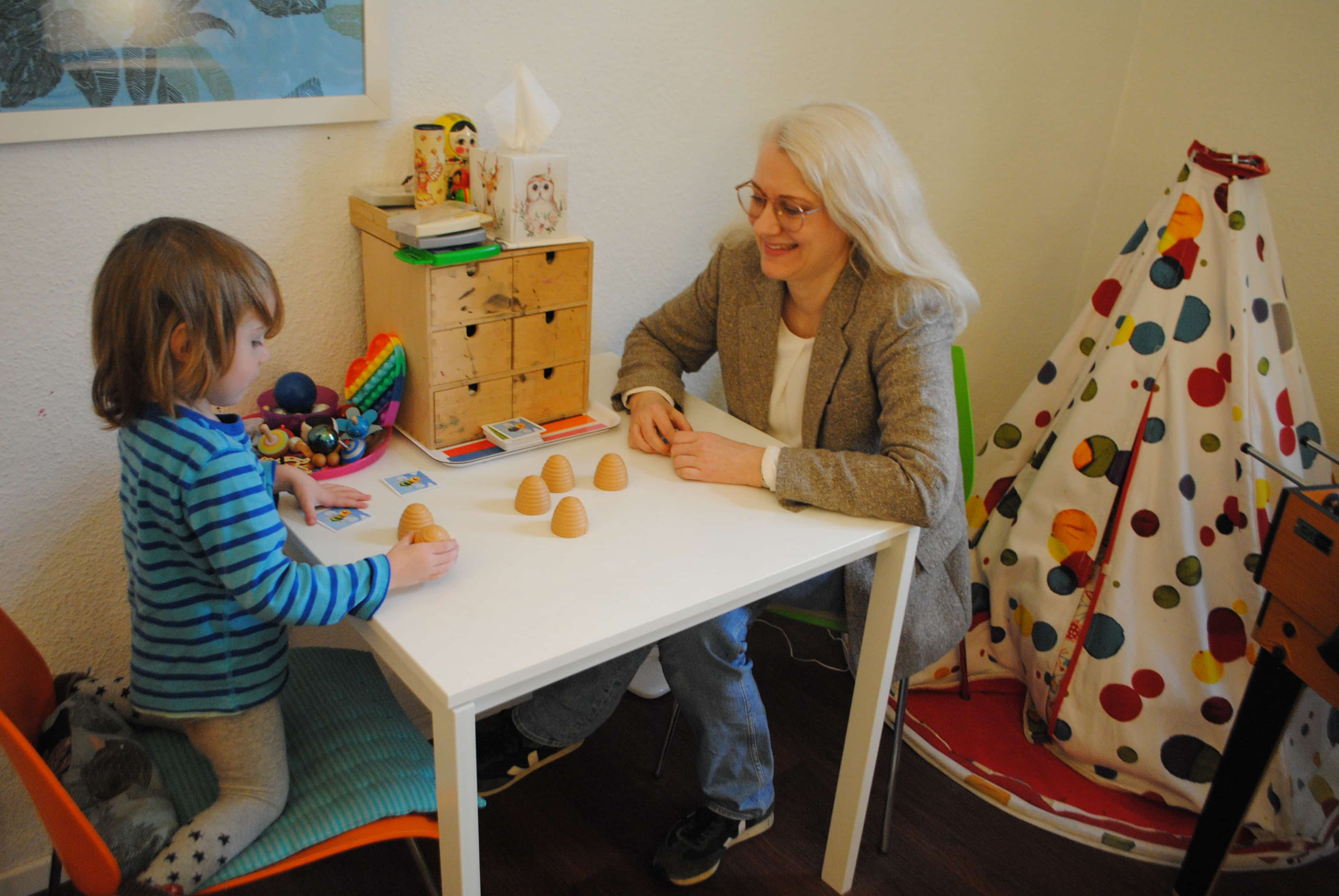 Verena Voß und ein Kind am Spieltisch in Ihrer KJP-Praxis