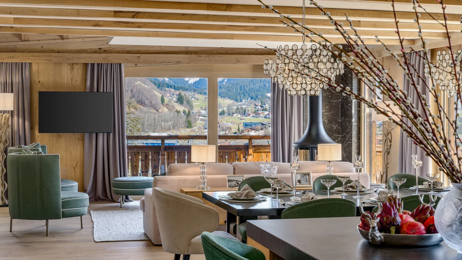 Silvretta Klosters open-plan living and dining area with exposed timber beams, statement chandelier, and mountain views