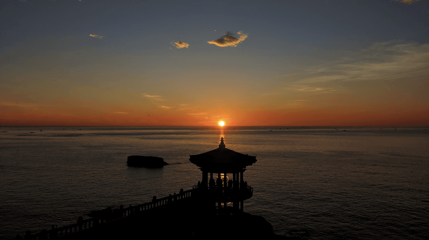 A minimalist wooden desk with a small lamp and an open notebook, situated in a bright, warm-lit room.