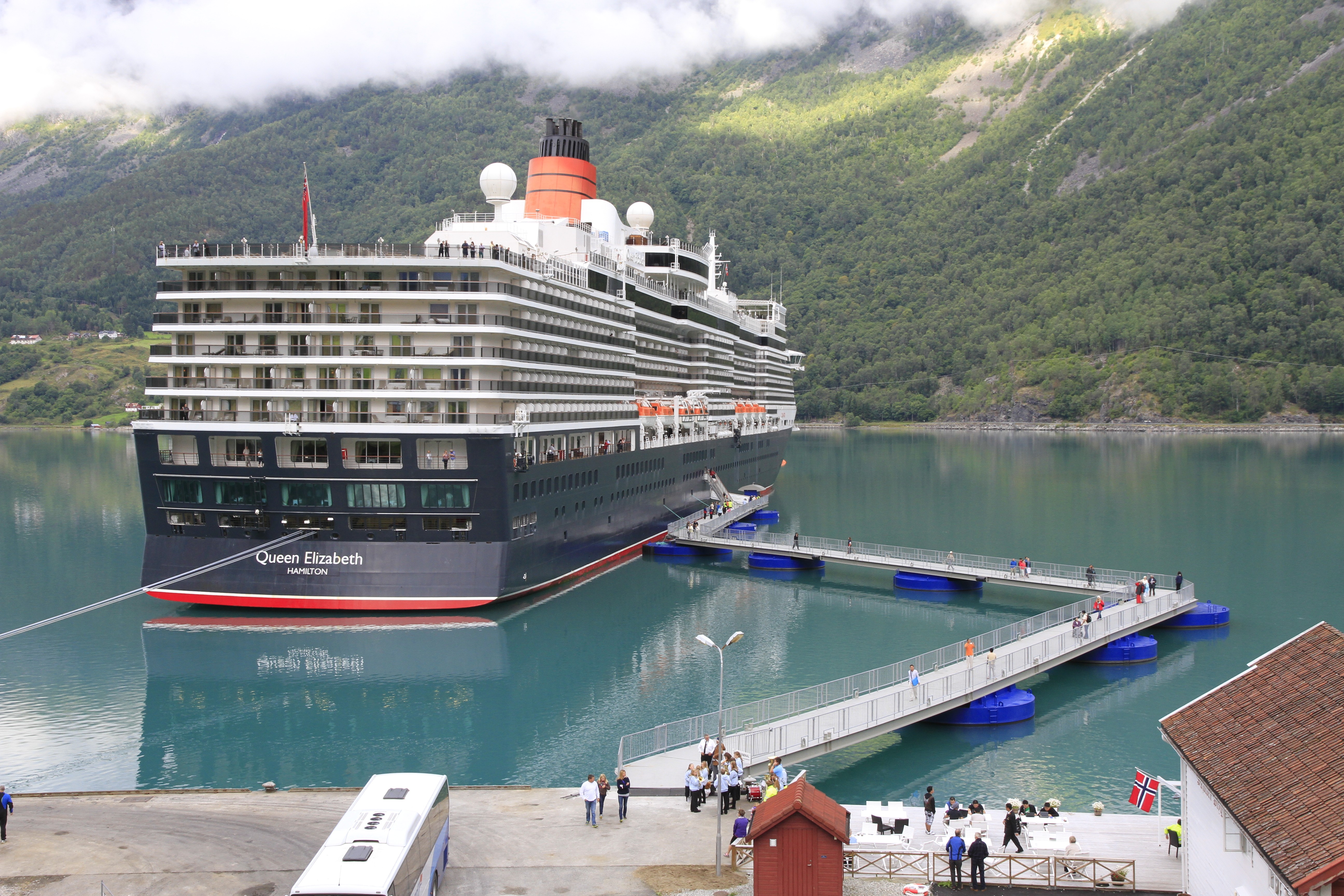 Cruise ship moored to a SeaWalk floating pier system extending from shore, enabling passenger access to a coastal destination without a permanent quay.