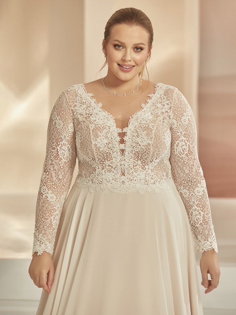 Detail van kanten lijfje en diepe V-hals van romantische trouwjurk met lange mouwen