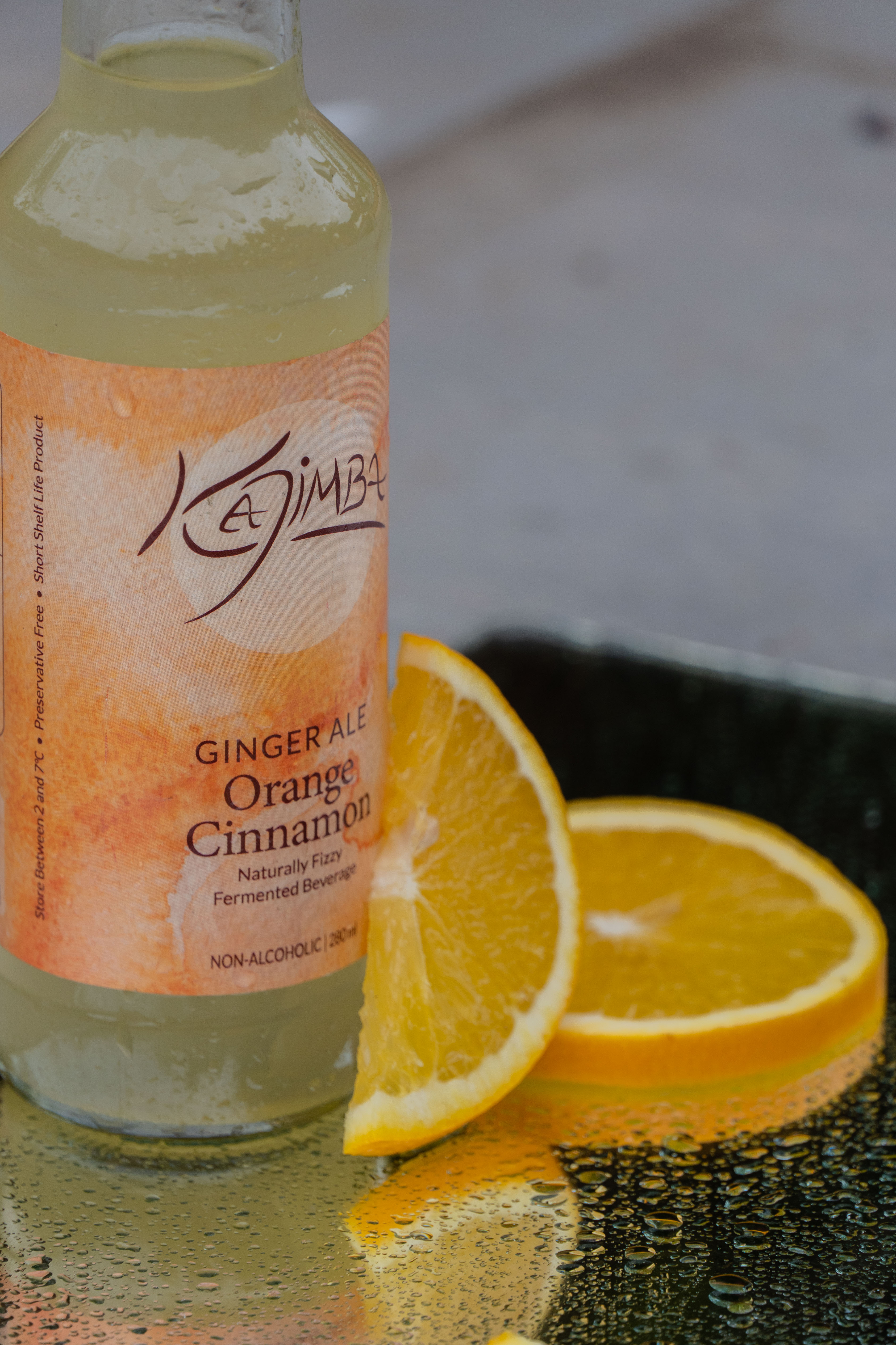 Orange Kajimba bottle next to a glass filled with Kajima and adorned by an orange slice.