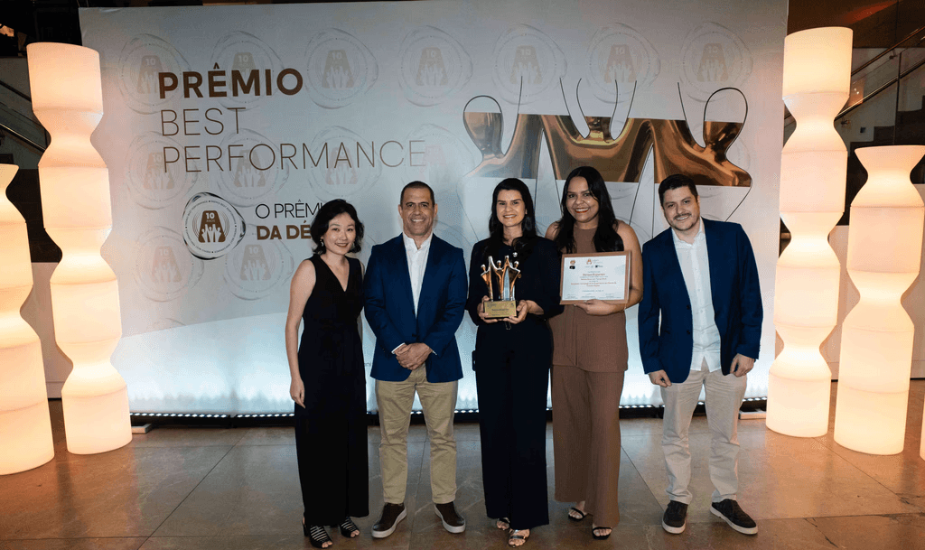 Executivos da Serasa Experian posando com troféu ouro e certificado no palco do Prêmio Best Performance 2025