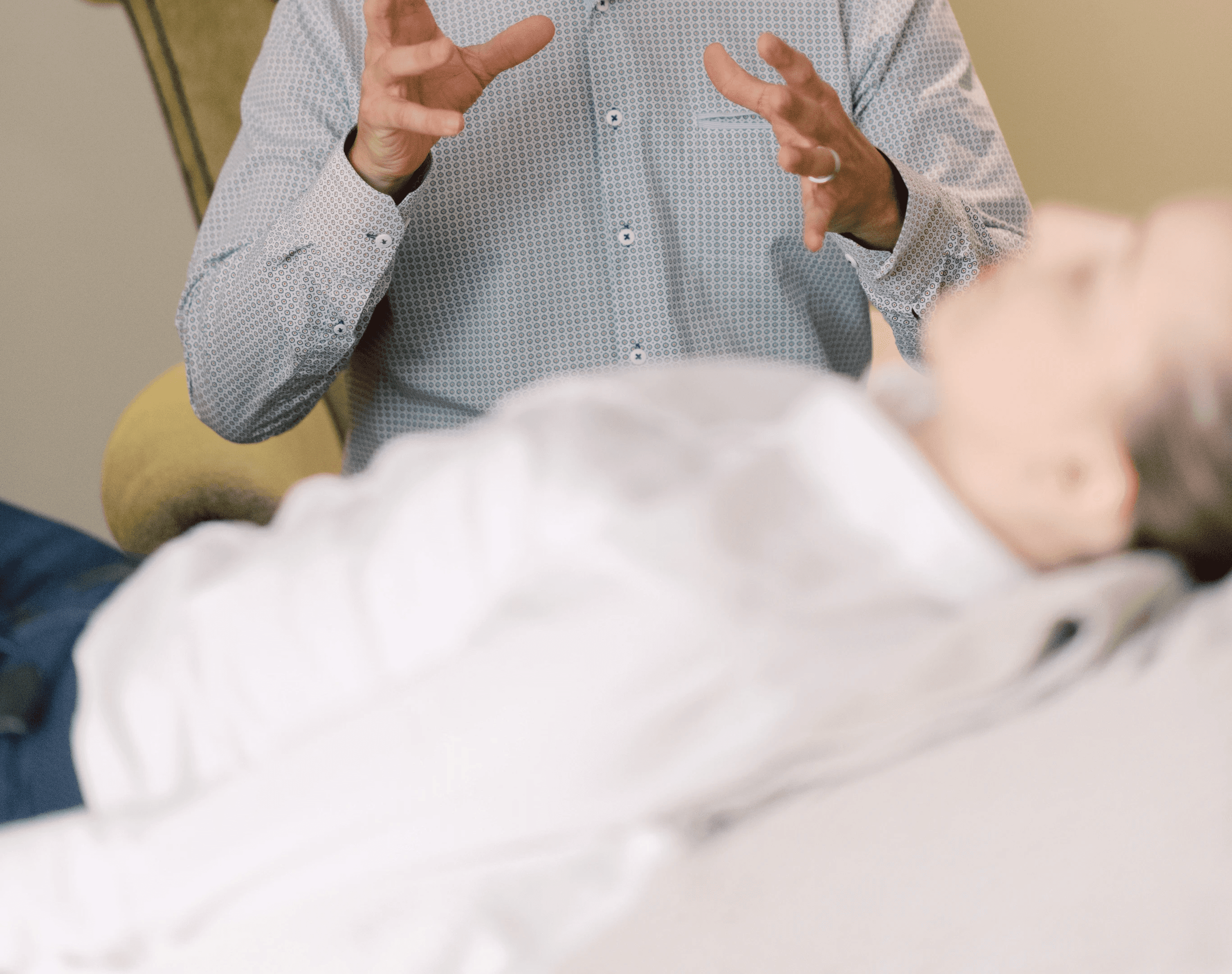 A person lying on a couch while a counsellor talks to them