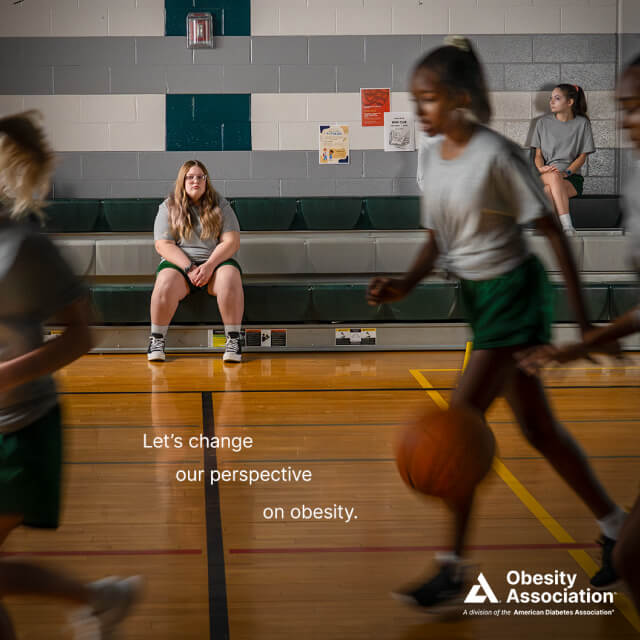 A girl sits alone on gym bleachers while others play basketball in Baltimore, with text reading Let's change our perspective on obesity. Obesity Association logo is visible, highlighting an independent advertising agency's brand strategy.
